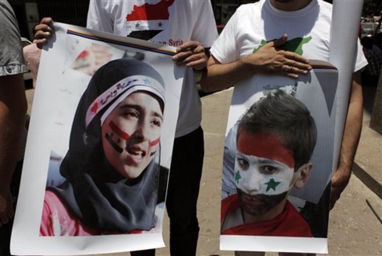 Two protesters carry posters Tuesday with pictures of unidentified relatives in Syria, with the Syrian flag colors painted on their faces during an anti-Syrian regime rally near the Syrian embassy in Cairo, Egypt.